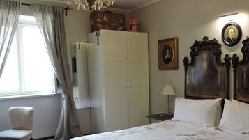 Une chambre à coucher avec un grand lit, un lustre, une armoire, une chaise et une fenêtre avec des rideaux.