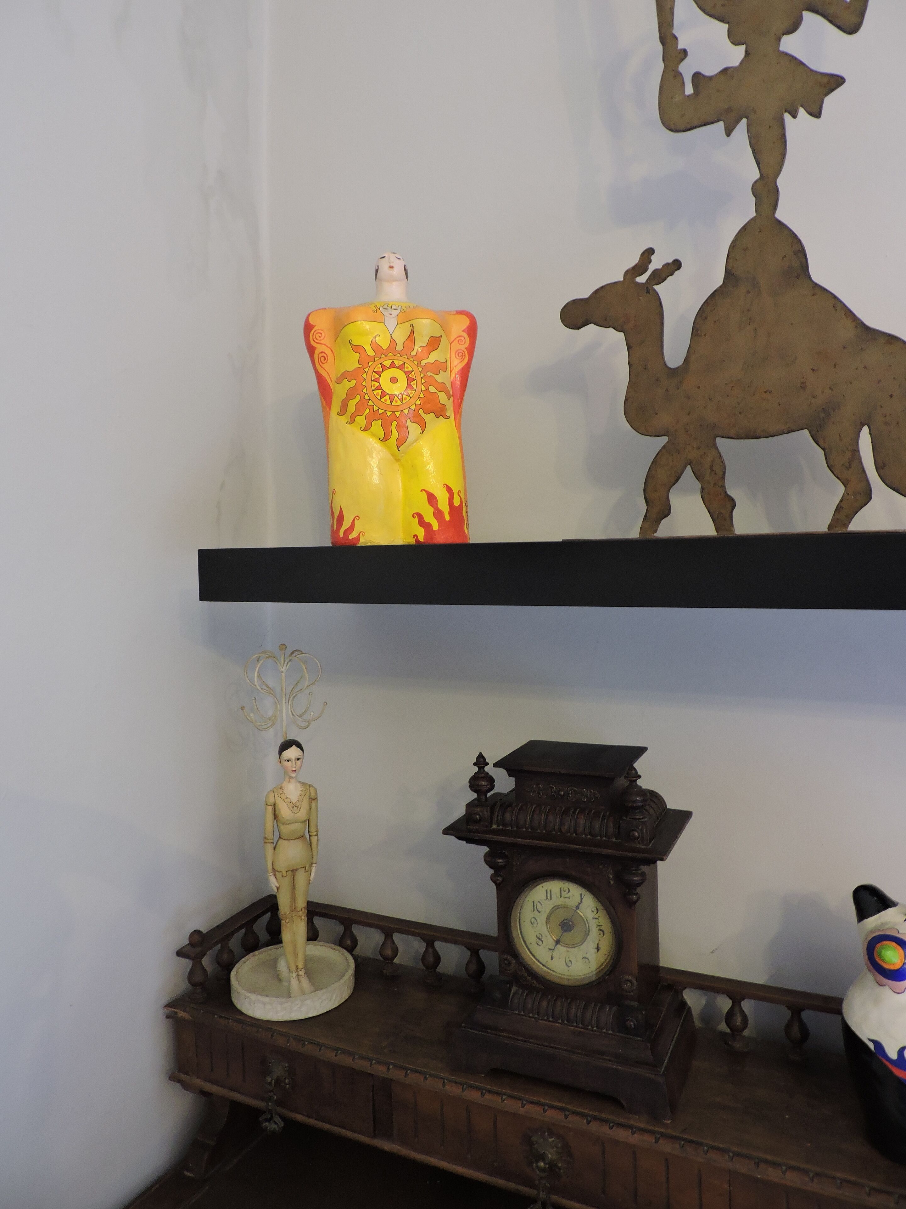 A shelf with a decorative vase, a figurine, and a clock.