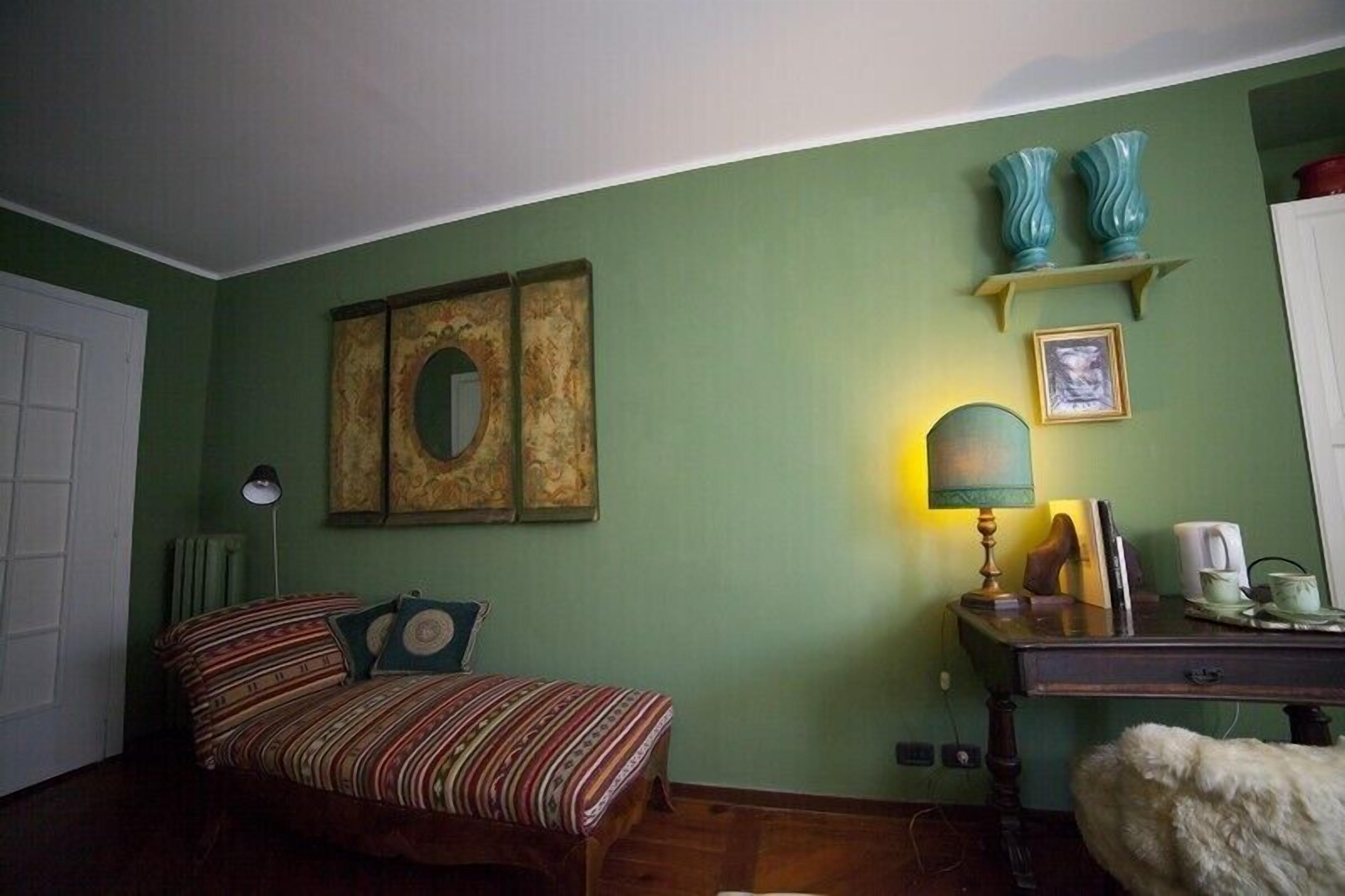 A room with a bed, a desk, a lamp, and decorative items on the wall.