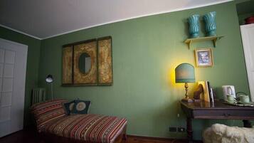 A room with a bed, a desk, a lamp, and decorative items on the wall.