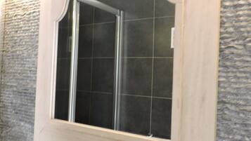A bathroom with a tiled wall, a sink with a faucet, and a mirror with a decorative frame.