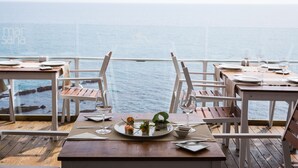 A dining area with tables set for two, overlooking the sea. - Hotel Boutique Milla de Plata (San Roque)