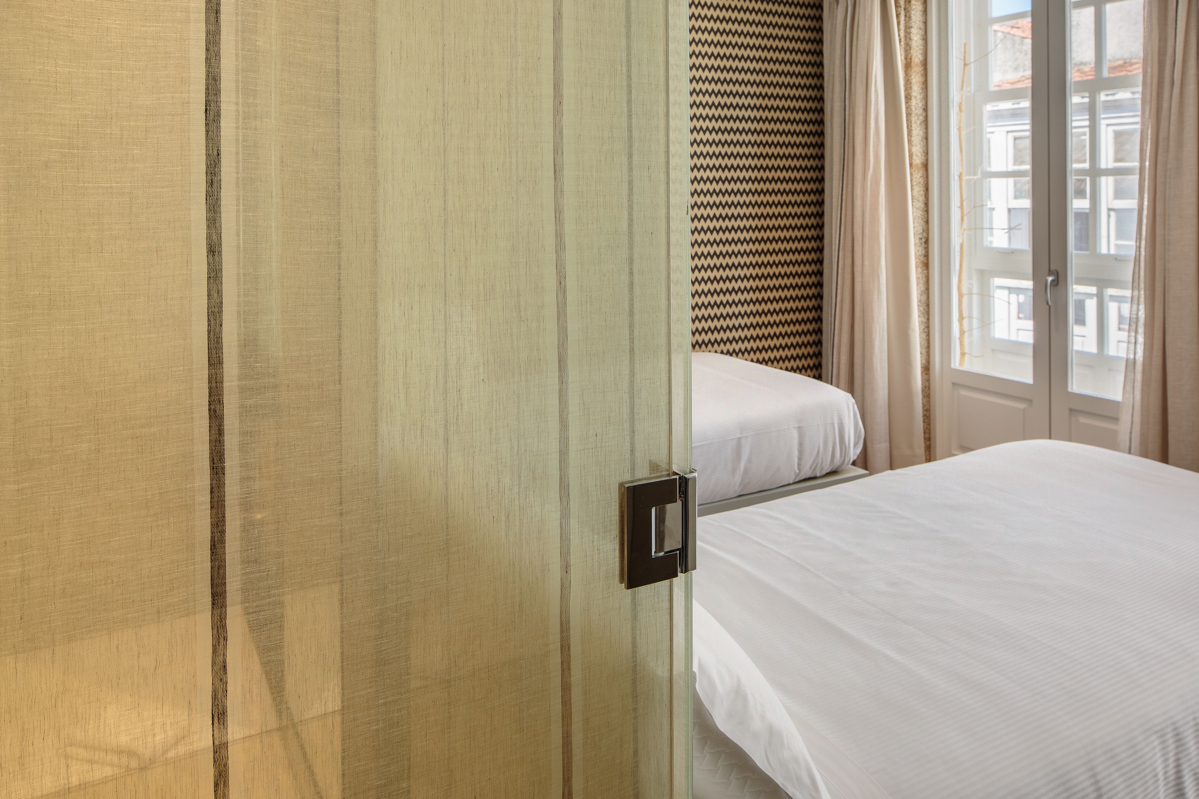 Una habitación de hotel con cama, armario y ventana con cortinas.