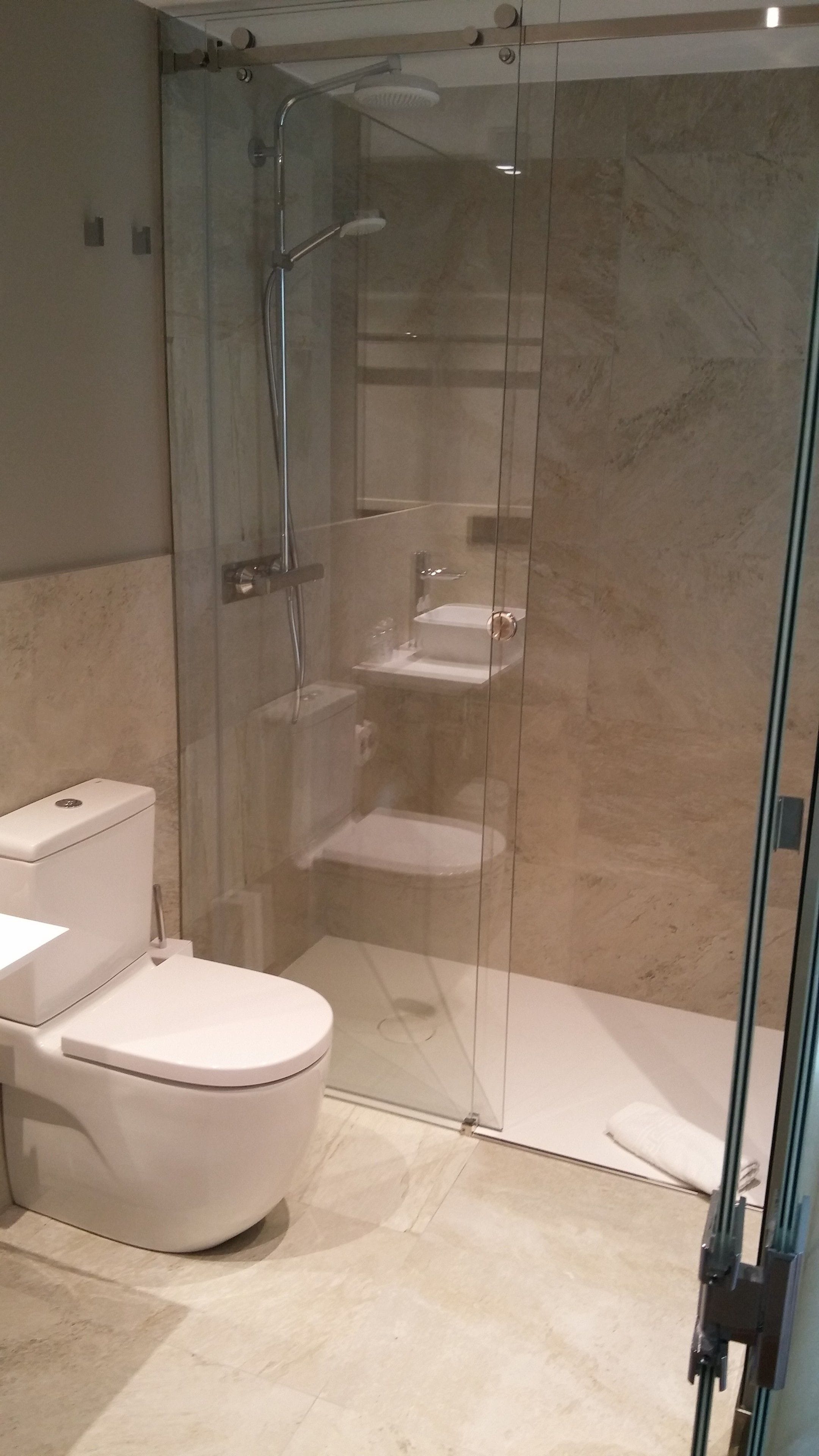 Un baño moderno con ducha de vidrio, inodoro y lavamanos.