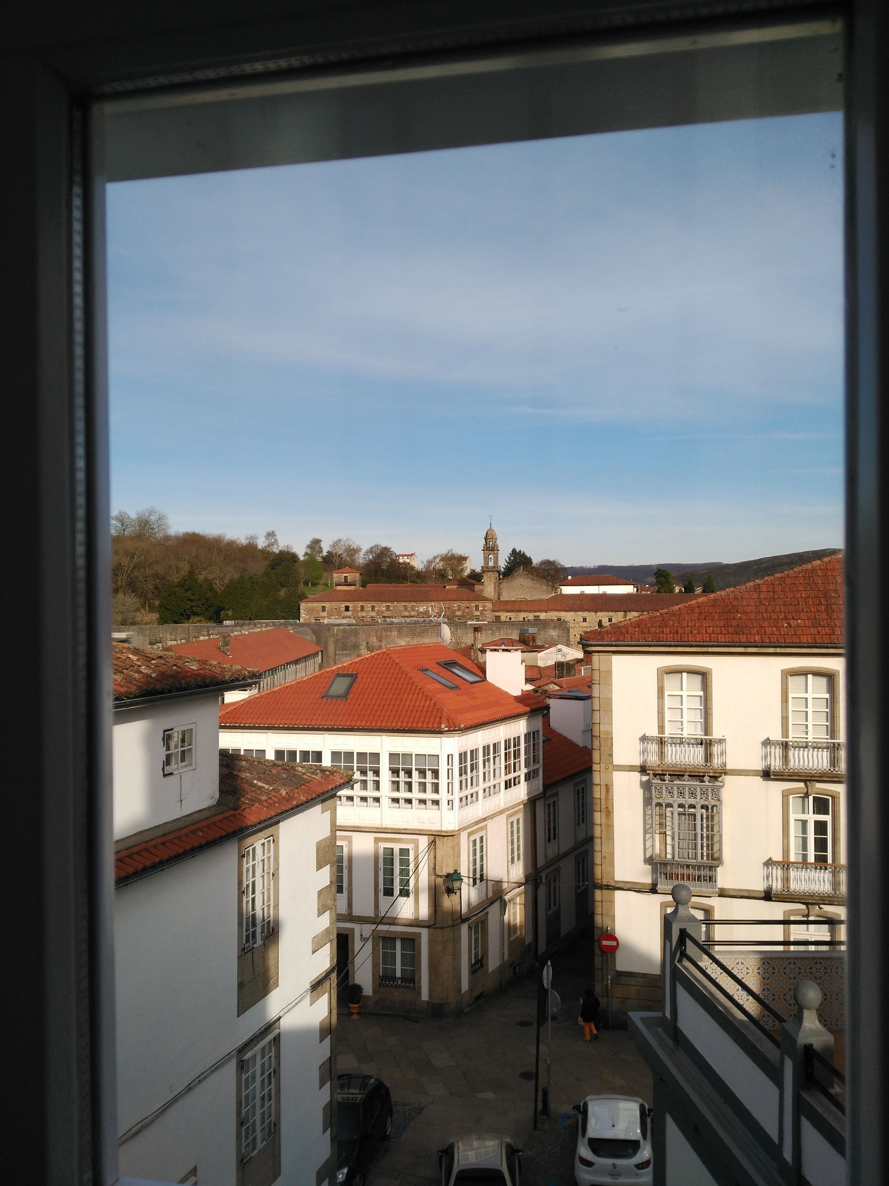 Vista de un pueblo con edificios, una torre y cielo despejado.