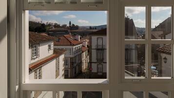 Une vue à travers la fenêtre d’un immeuble à plusieurs étages, présentant une architecture traditionnelle avec des toits en tuiles et un mélange de balcons et de fenêtres.