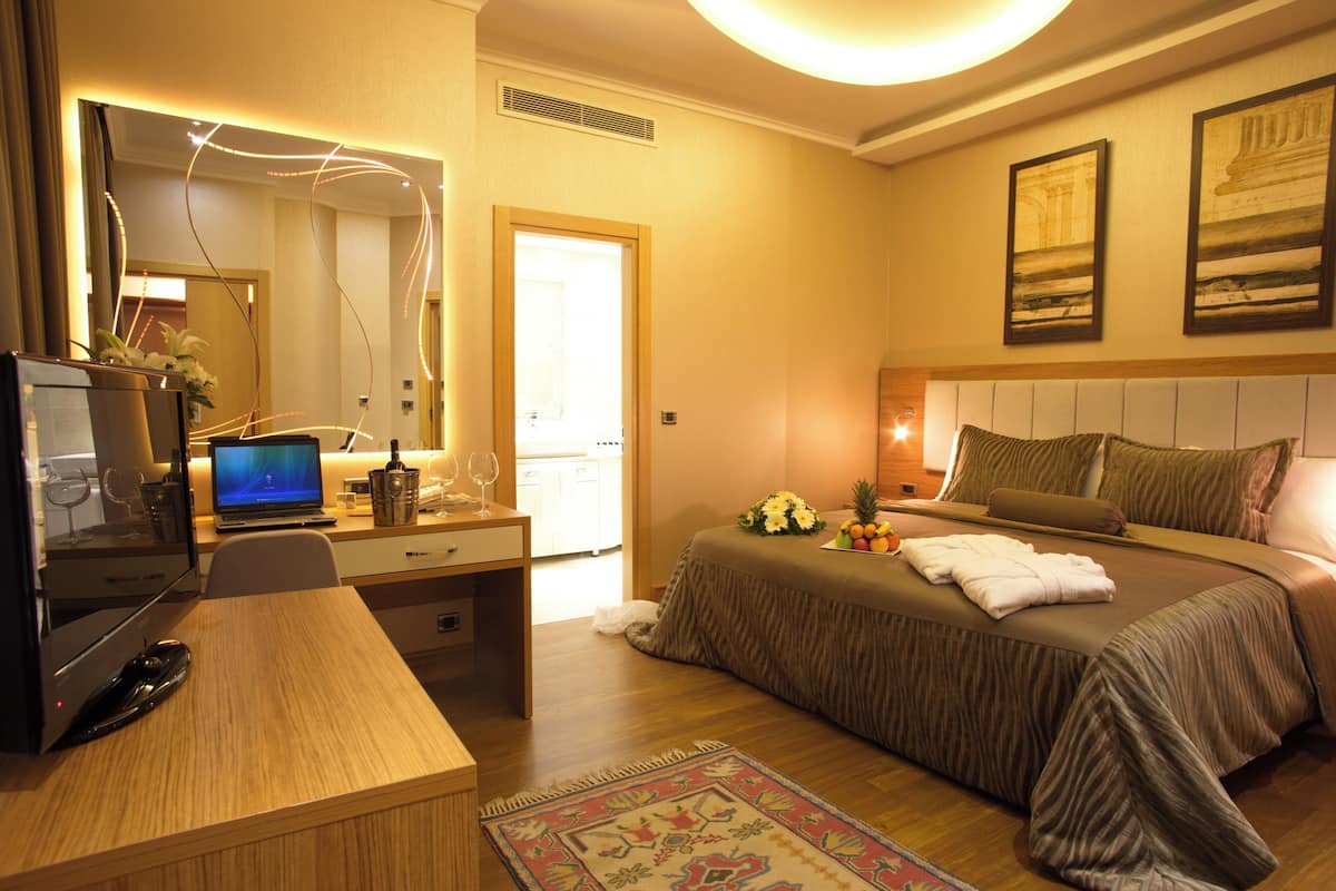 Une chambre d’hôtel équipée d’un lit, d’un bureau, d’un ordinateur et d’un miroir.