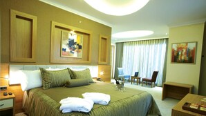 A hotel room with a large bed, a desk, a chair, and a view of the outdoors. - dovsOtel (Manisa)