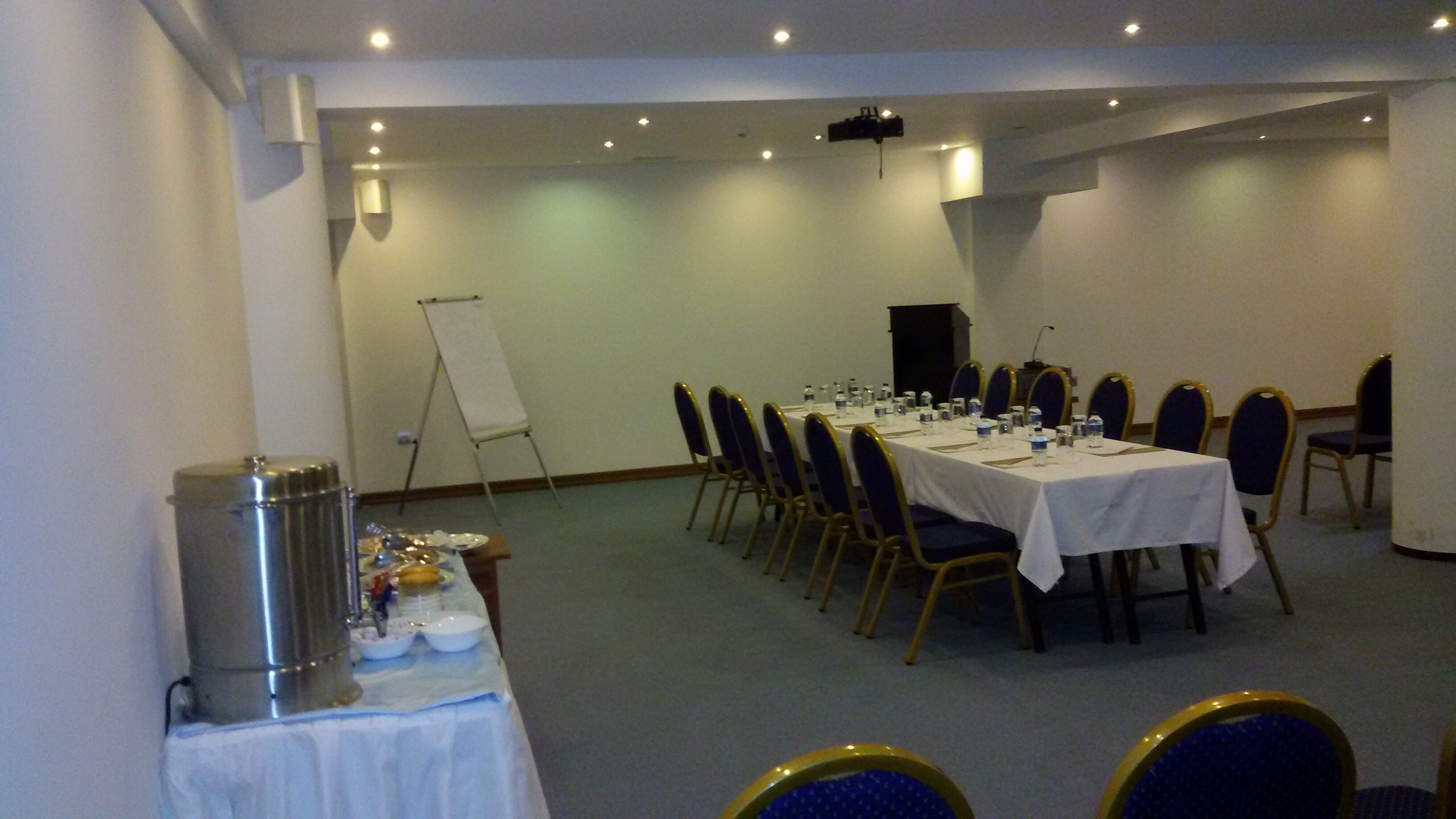 A conference room with a long table set for a meeting, chairs, a whiteboard, and a projector.