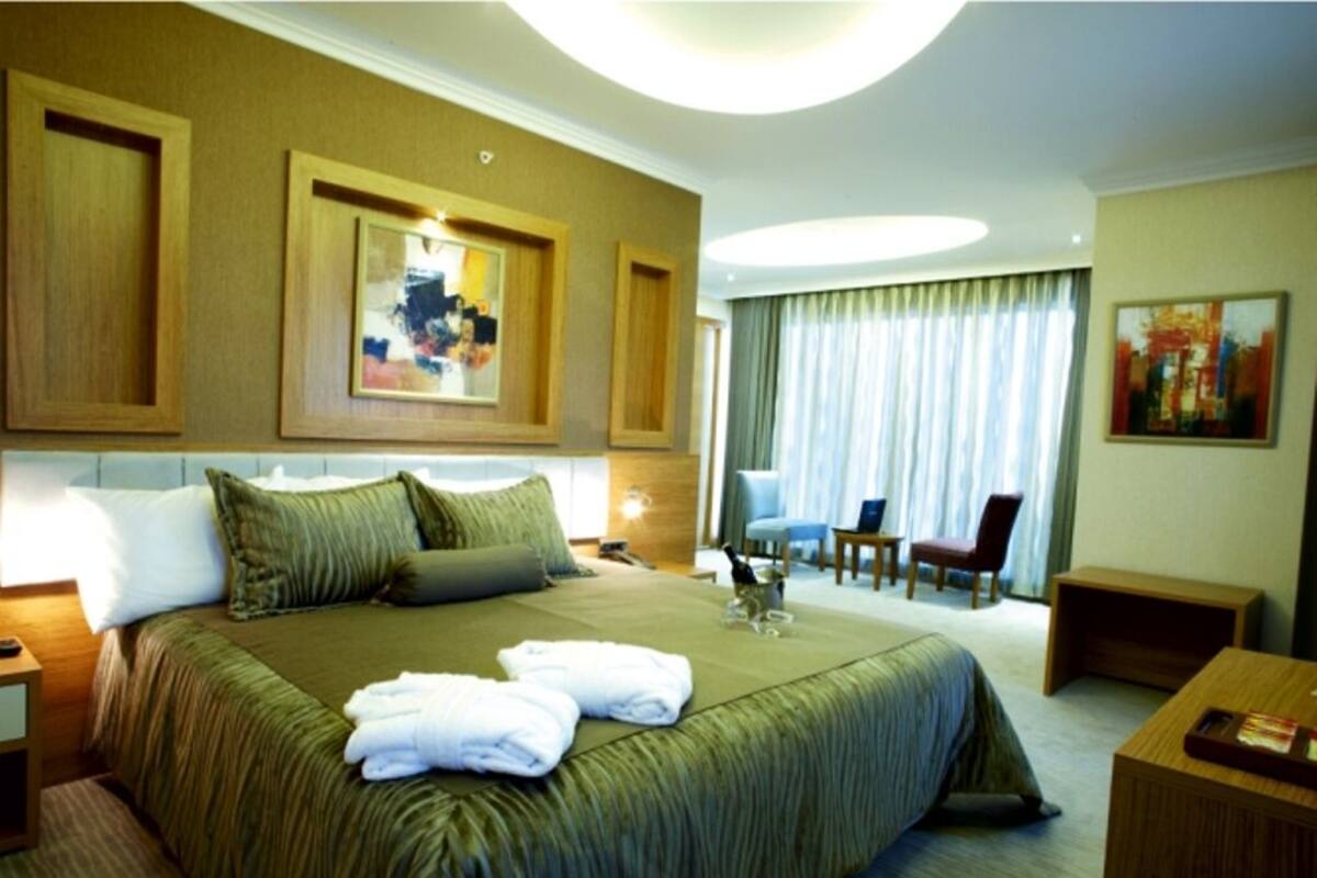 Habitación de hotel con una cama grande, un escritorio, una silla y vistas a la ciudad desde la ventana.
