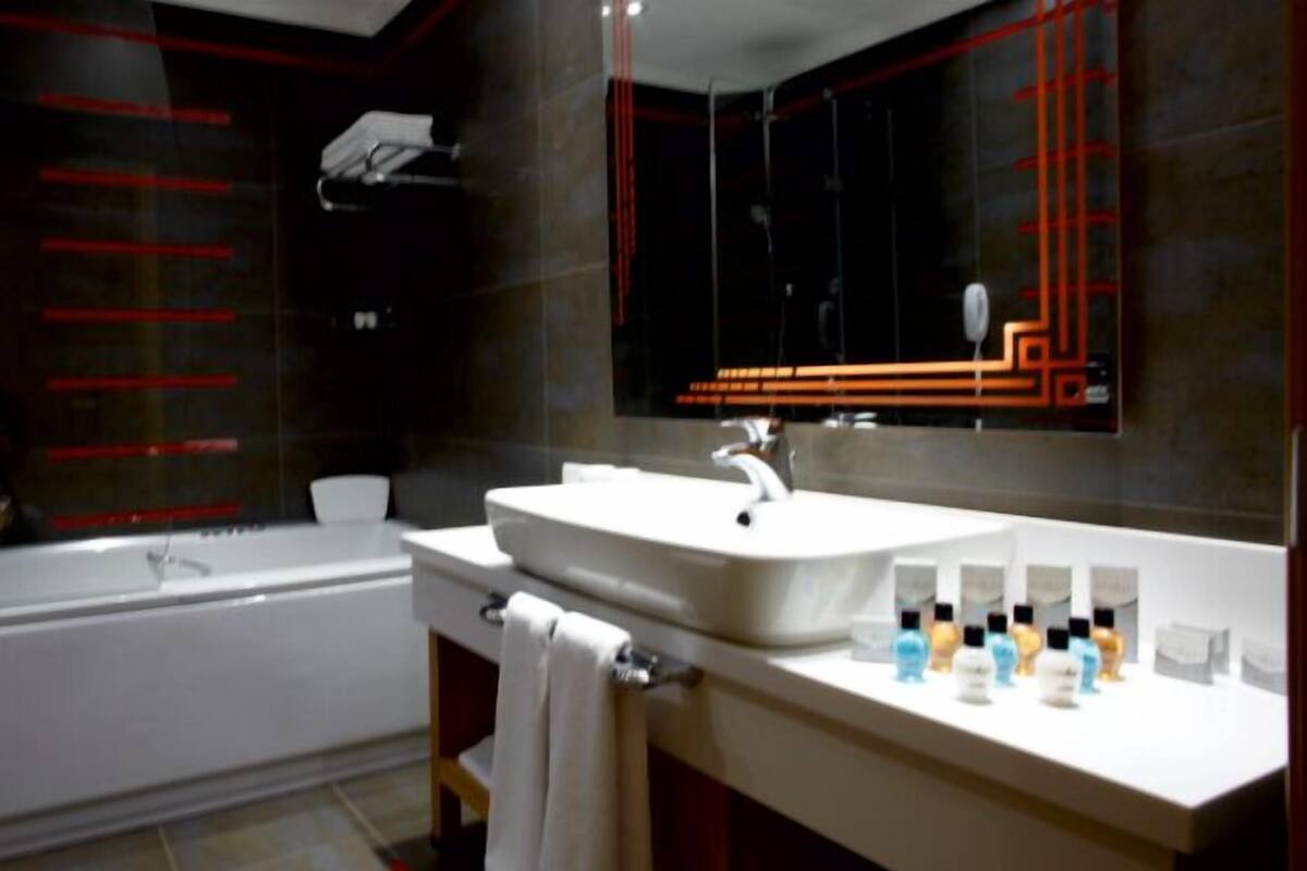 A modern bathroom with a white sink, a large mirror, and a bathtub.