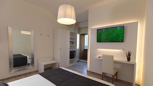 Una habitación de hotel moderna con una cama grande, un escritorio con una silla, un televisor montado en la pared y un armario.