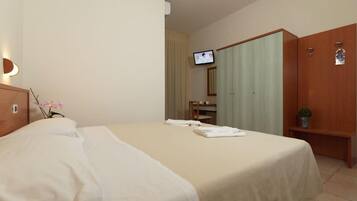 Una camera d'albergo con un letto, una televisione, una scrivania e un armadio.