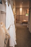 A hotel room with a bed, a chair, and a robe hanging on the wall.