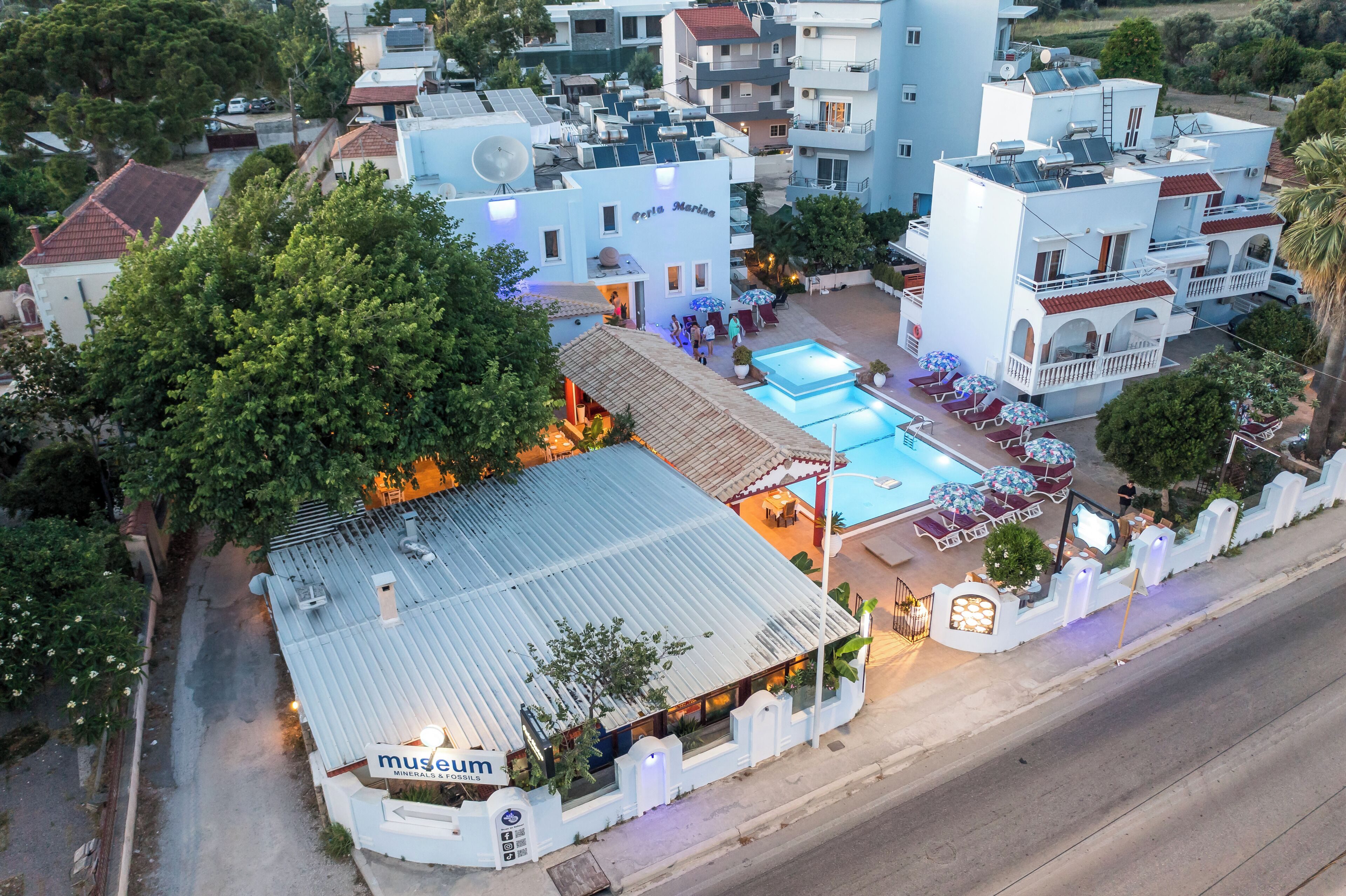 Un hotel con piscina, mobiliario exterior y un letrero para un museo.