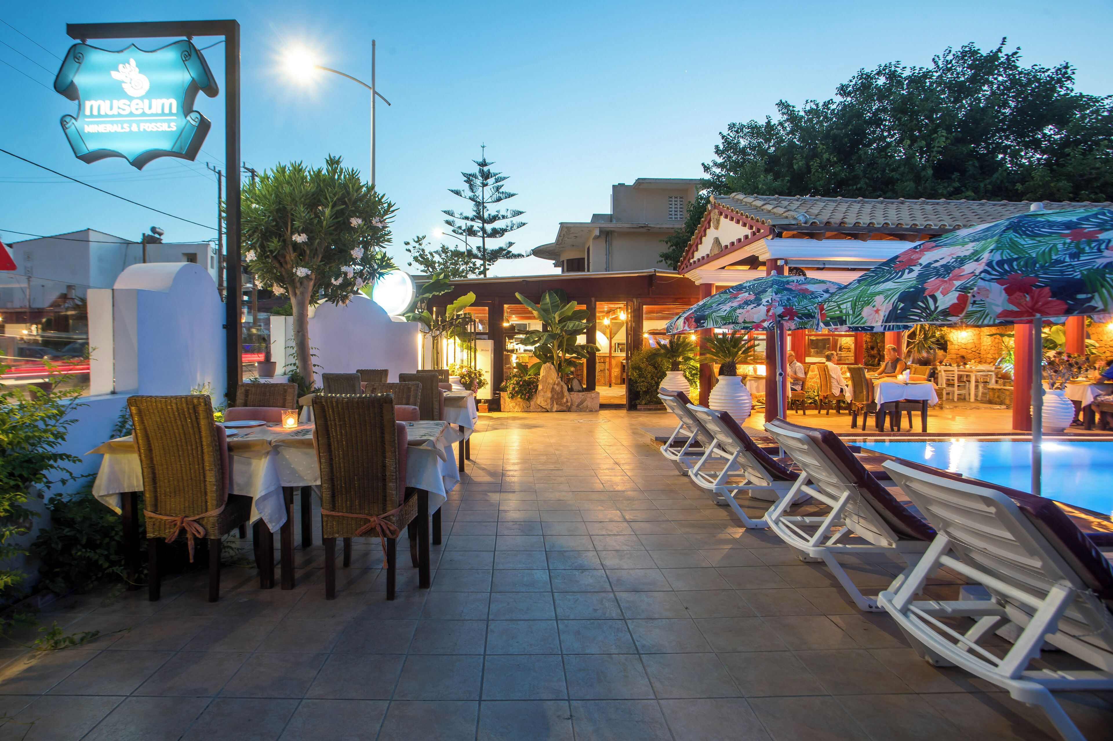 A restaurant with outdoor seating, a pool, and a sign for a museum.
