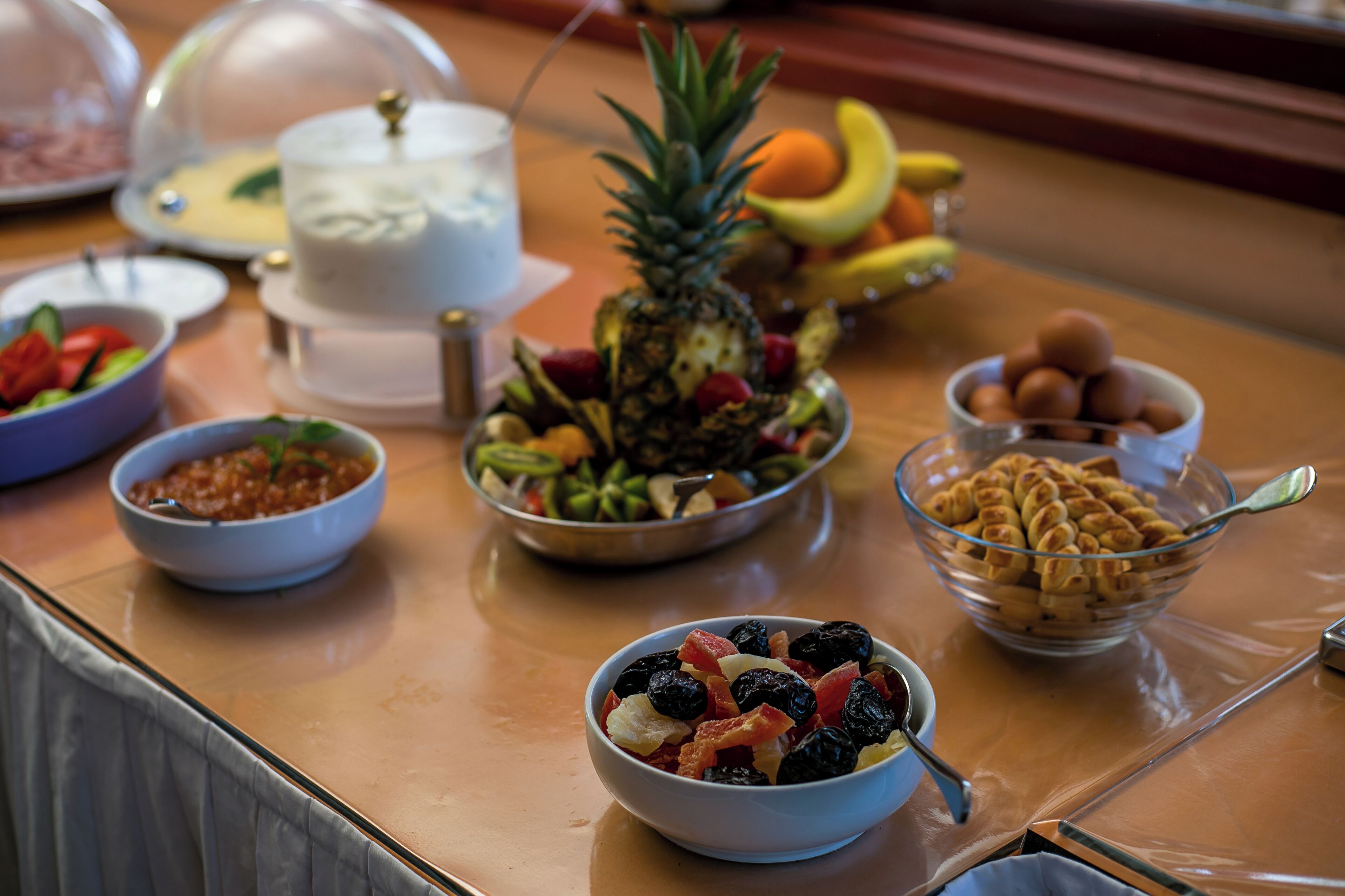 A buffet table with various food items including fruits, a cake, and a bowl of cookies.