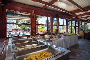 A buffet with various food options, a pool view, and a covered outdoor seating area. - Perla Marina (Rhodes)