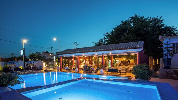 A swimming pool with a restaurant adjacent to it, featuring outdoor seating and a covered area. - Perla Marina (Rhodes)