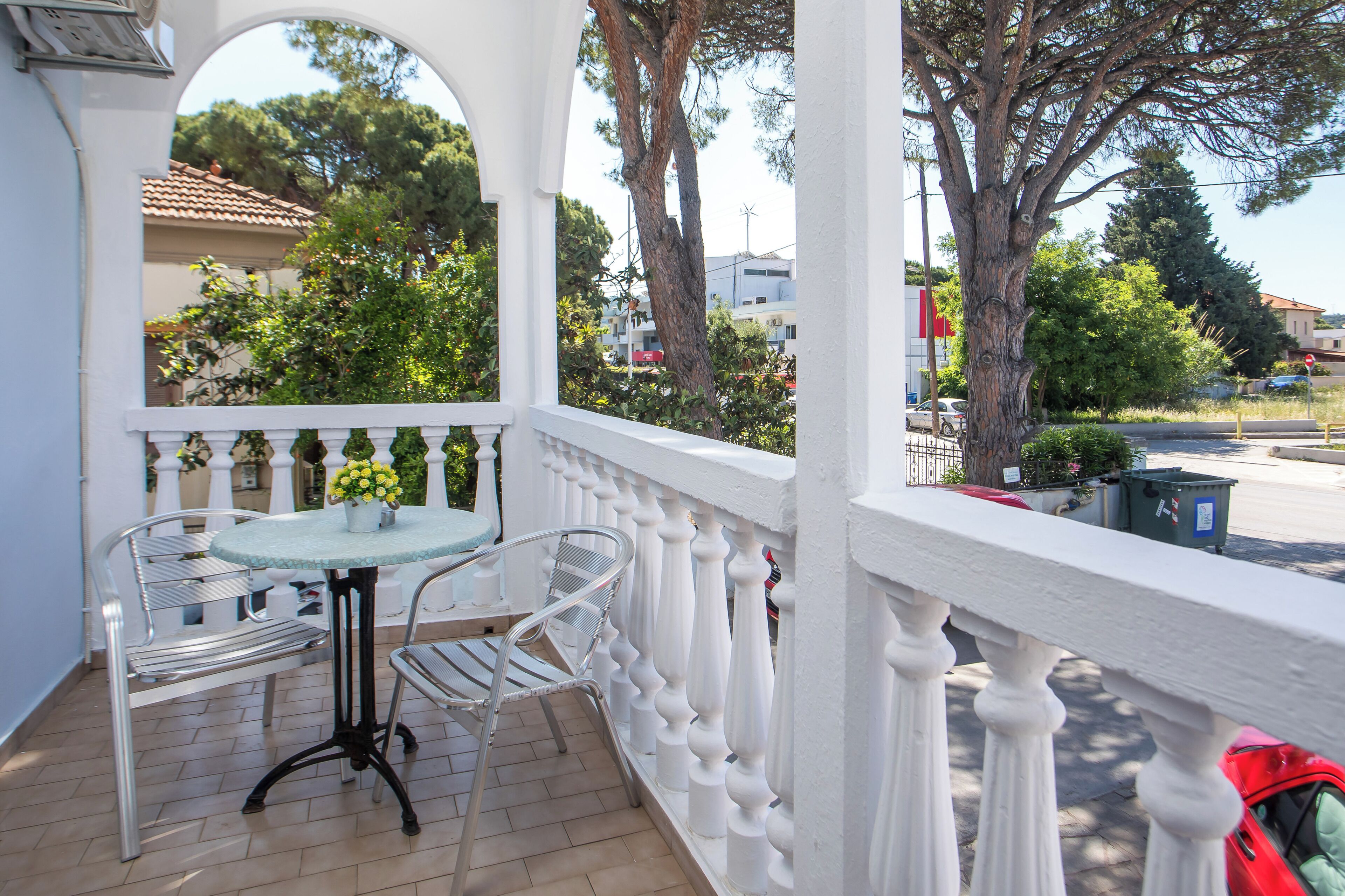 A balcony with a white railing, a table, and two chairs.