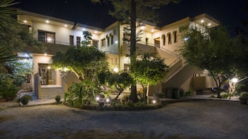 A multi-story building with a well-lit entrance, outdoor seating area, and a staircase leading to the upper levels.