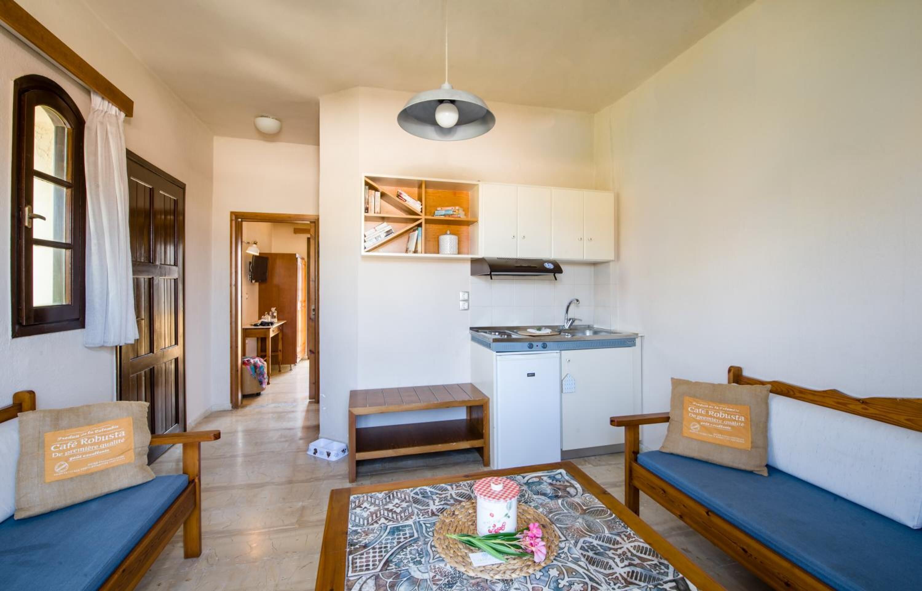 Un espacio habitable compacto con kitchenette, un sofá, una banca y una mesa estampada.