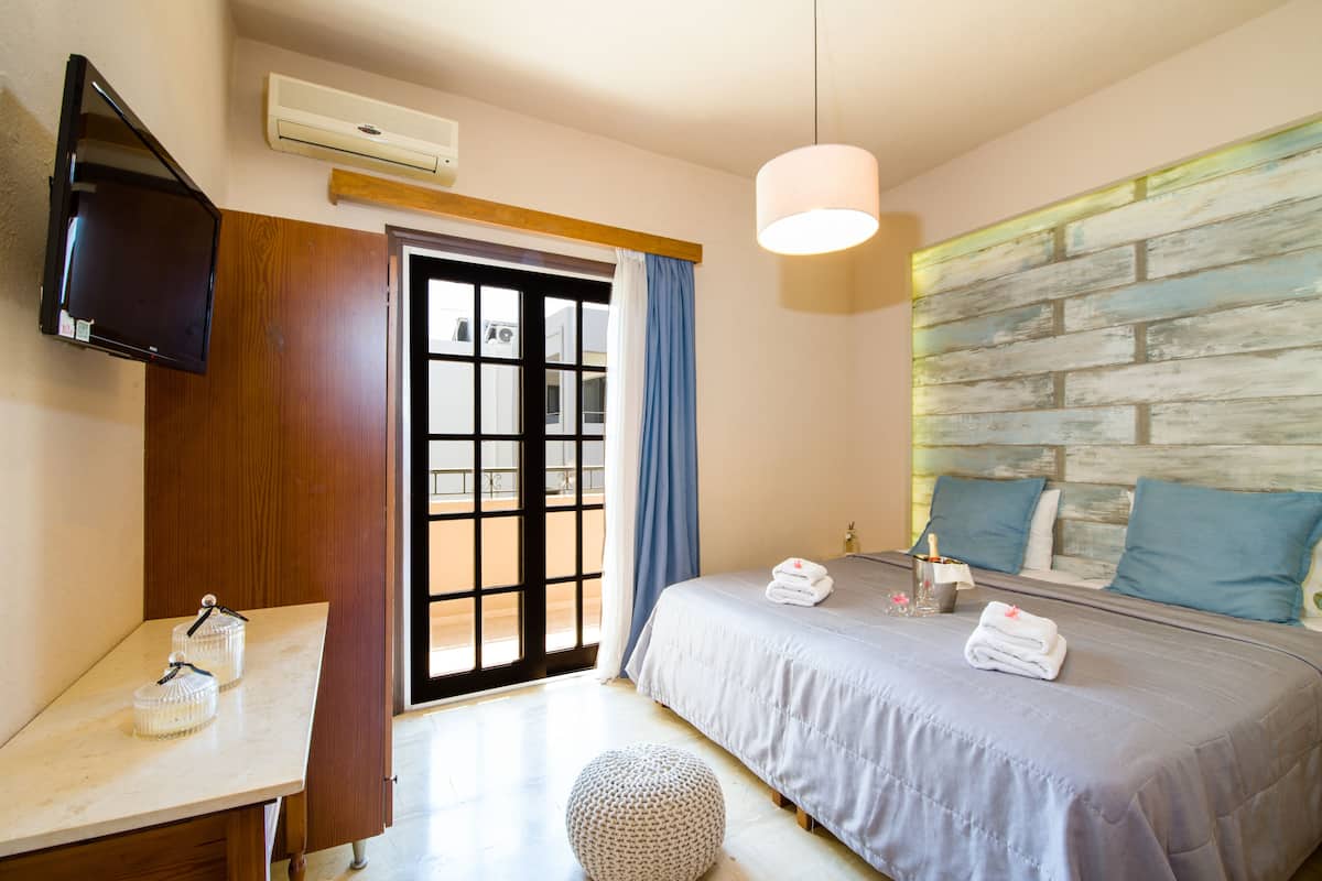 A hotel room with a bed, bedside table, TV, and a view through the door.