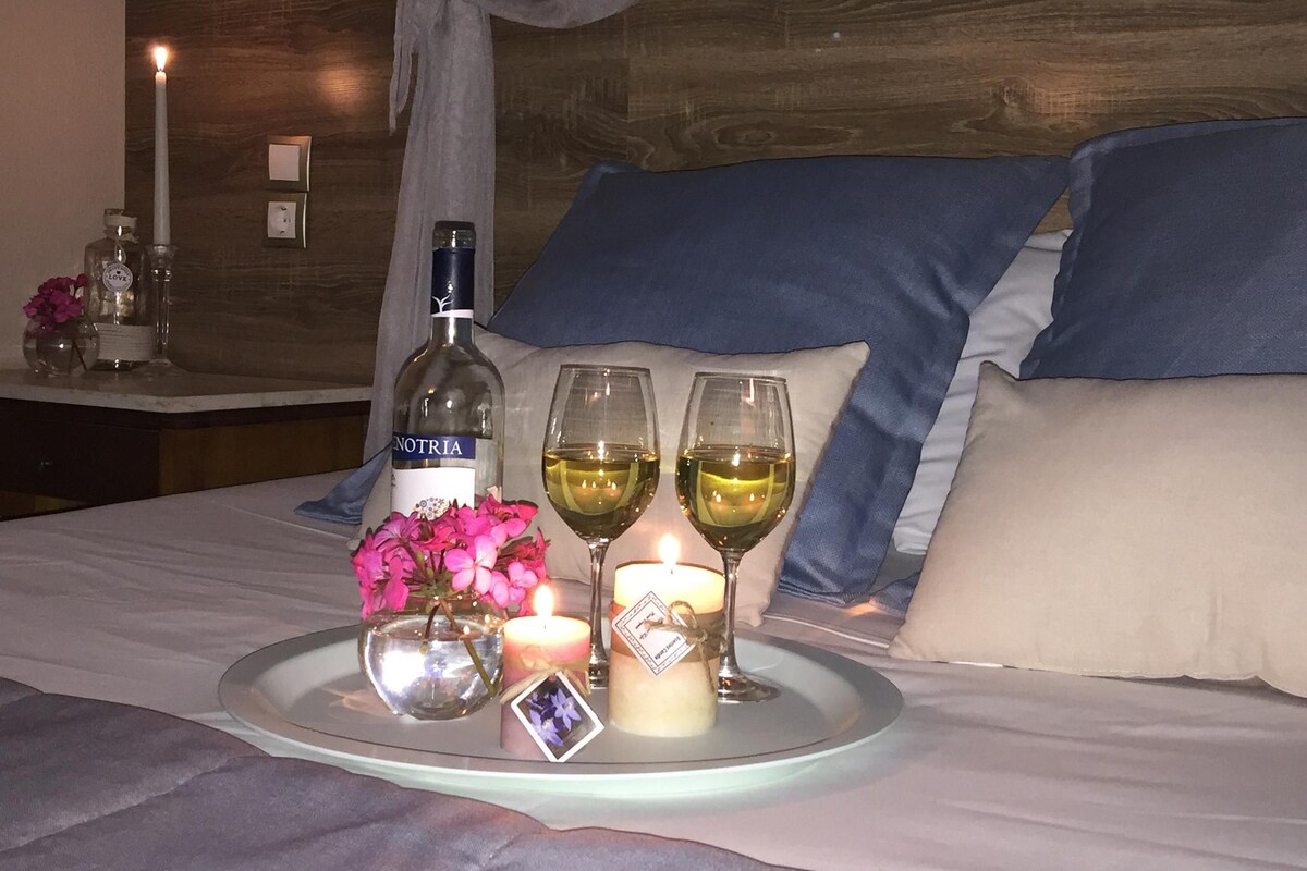 Un lit avec un plateau contenant du vin, des fleurs et des bougies.