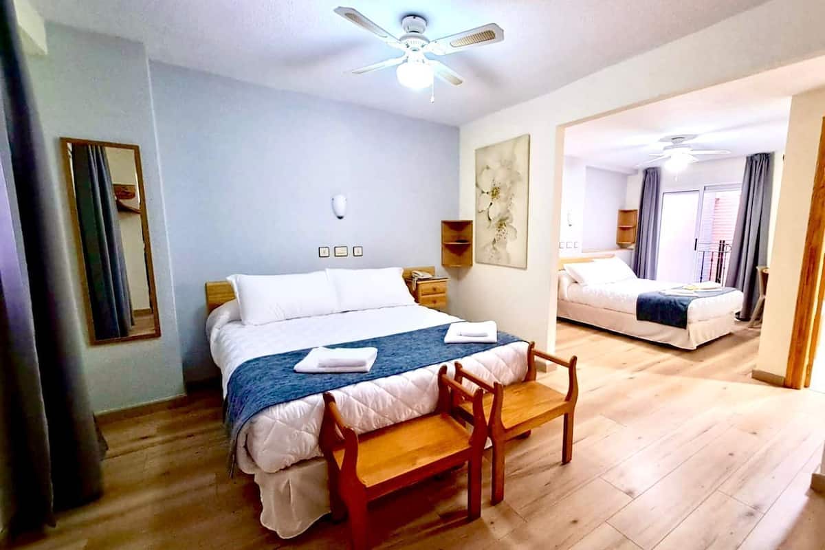 Ein Hotelzimmer mit Bett, Schreibtisch, Stuhl, Deckenventilator und Spiegel.