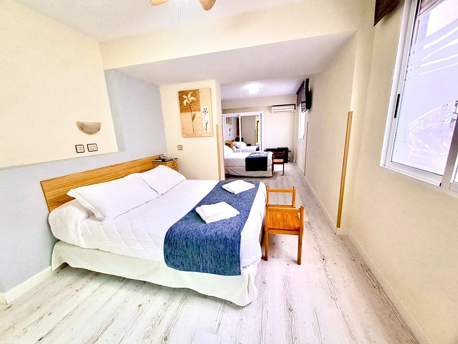 Une chambre à coucher avec un lit en bois, une table de chevet, une chaise et une fenêtre.