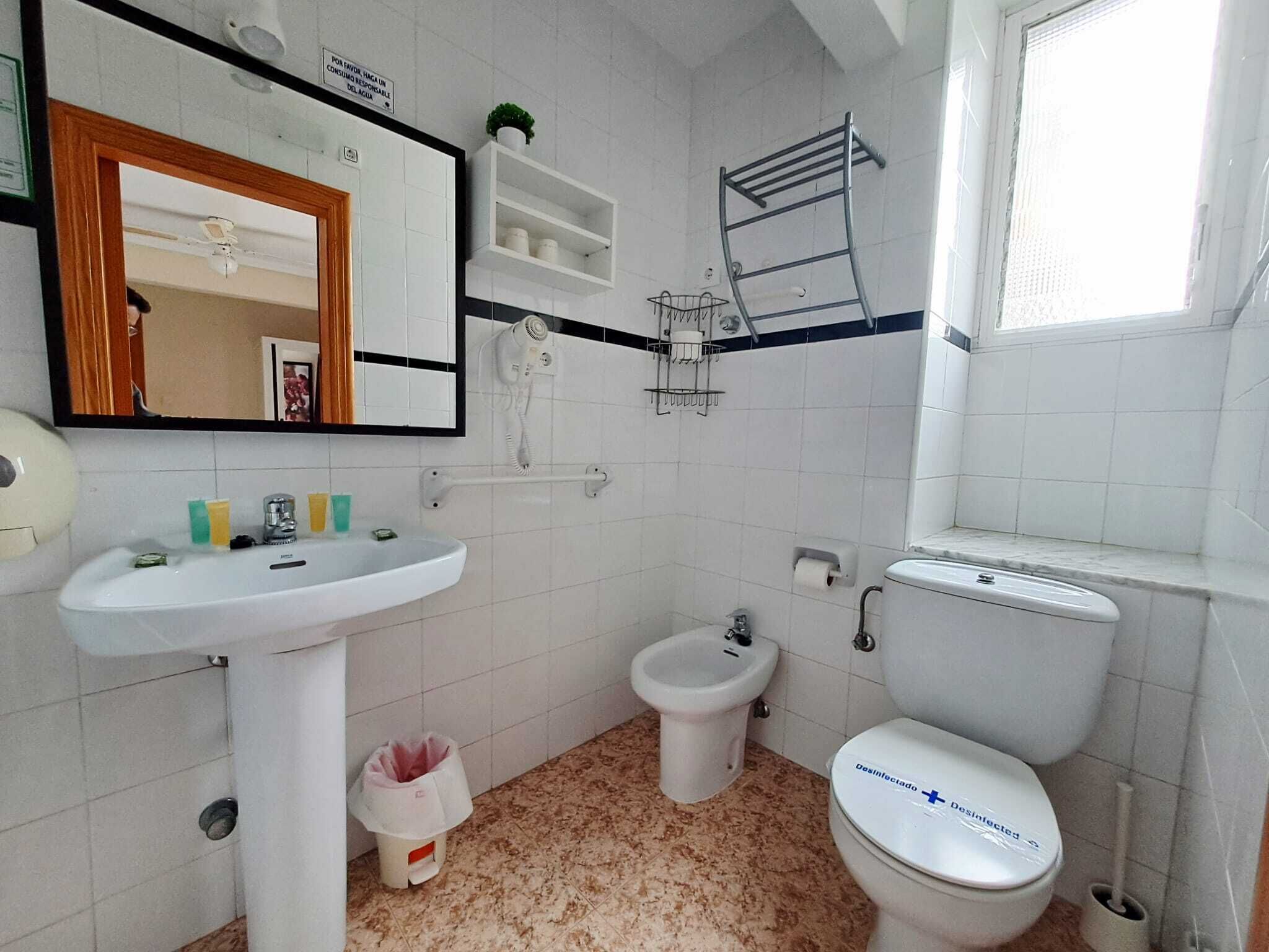Une salle de bain équipée d’un lavabo, d’un bidet, de toilettes, d’un miroir et d’un porte-serviettes.