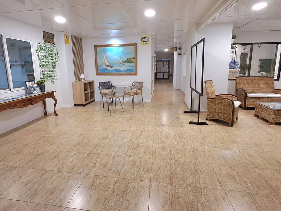 A hotel lobby with a reception desk, seating area, and a painting on the wall.