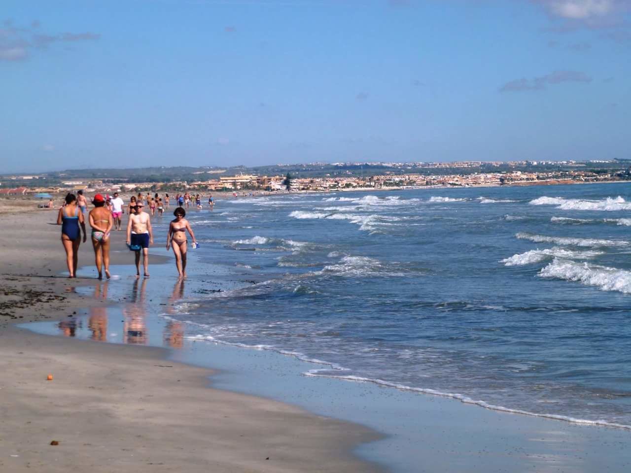 Ein Strand mit Menschen, die am Ufer entlanggehen.