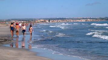 Ein Strand mit Menschen, die am Ufer entlanggehen.