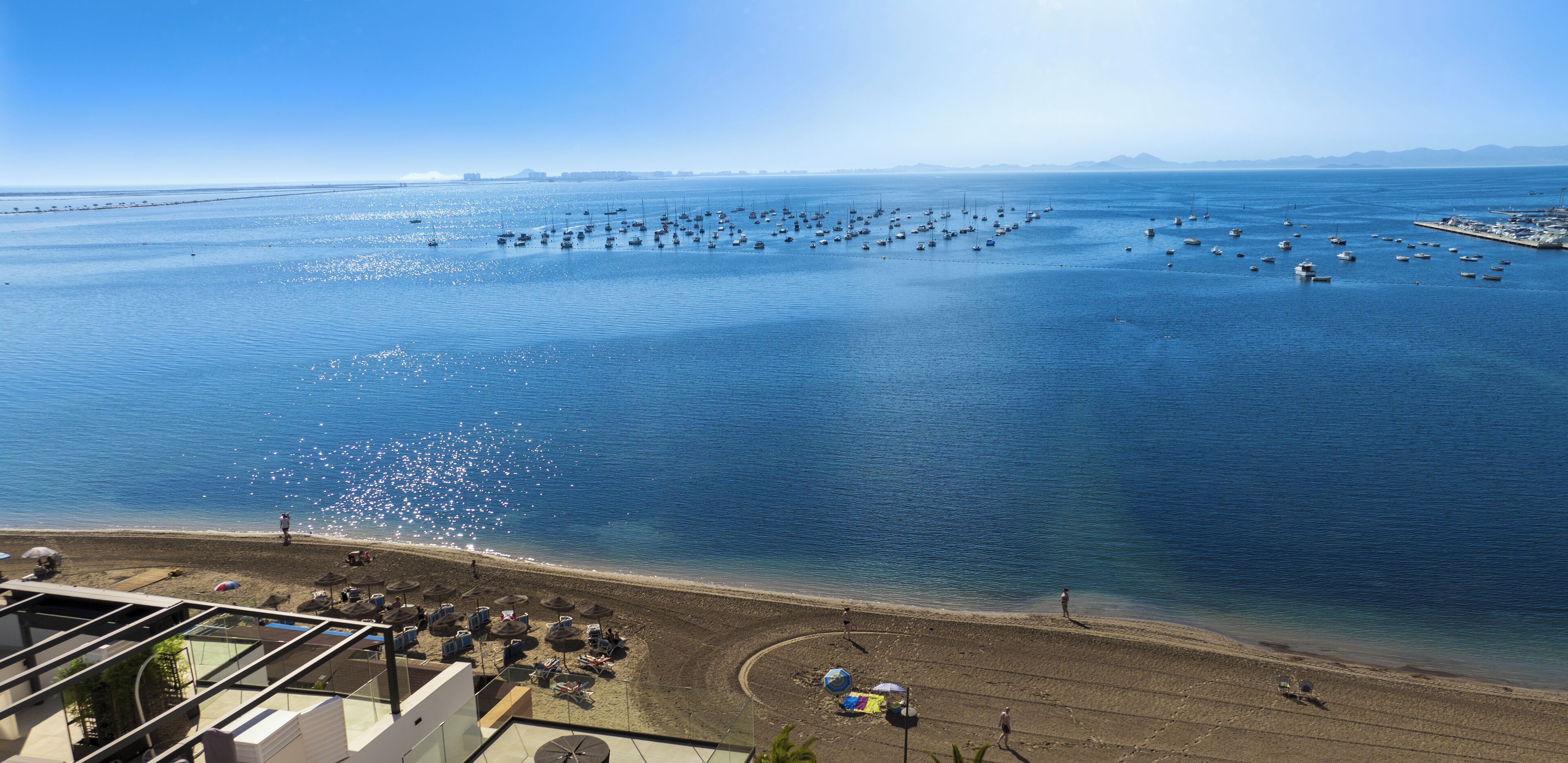 A coastal view with a beach, boats, and a clear sky.