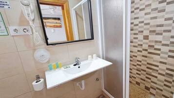 Un baño con lavamanos, espejo, inodoro y ducha.