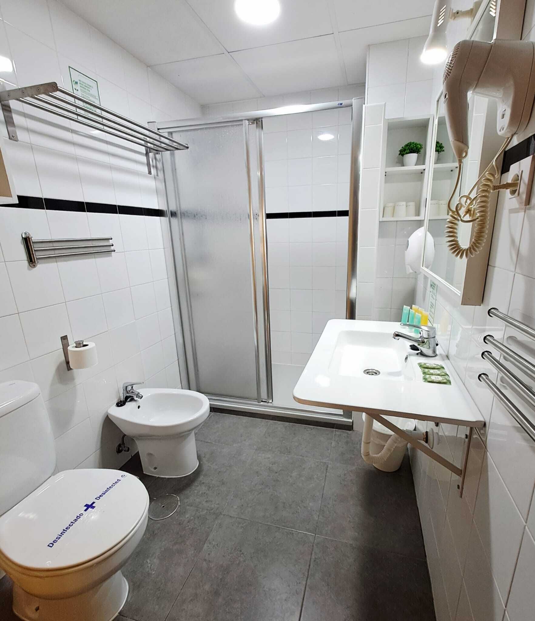 A modern bathroom with a toilet, bidet, shower, and sink.