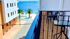 Un balcón con vista al mar, un edificio de diseño moderno y una barandilla de metal.