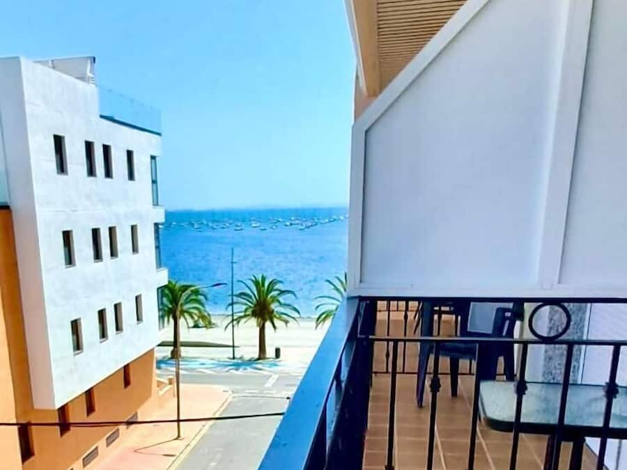 Un balcon avec vue sur la mer, un immeuble au design moderne et une rambarde en métal.