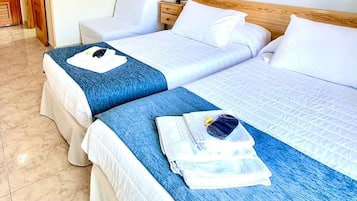 Habitación de hotel con dos camas, cabecero de madera, lámpara de pared y una puerta.