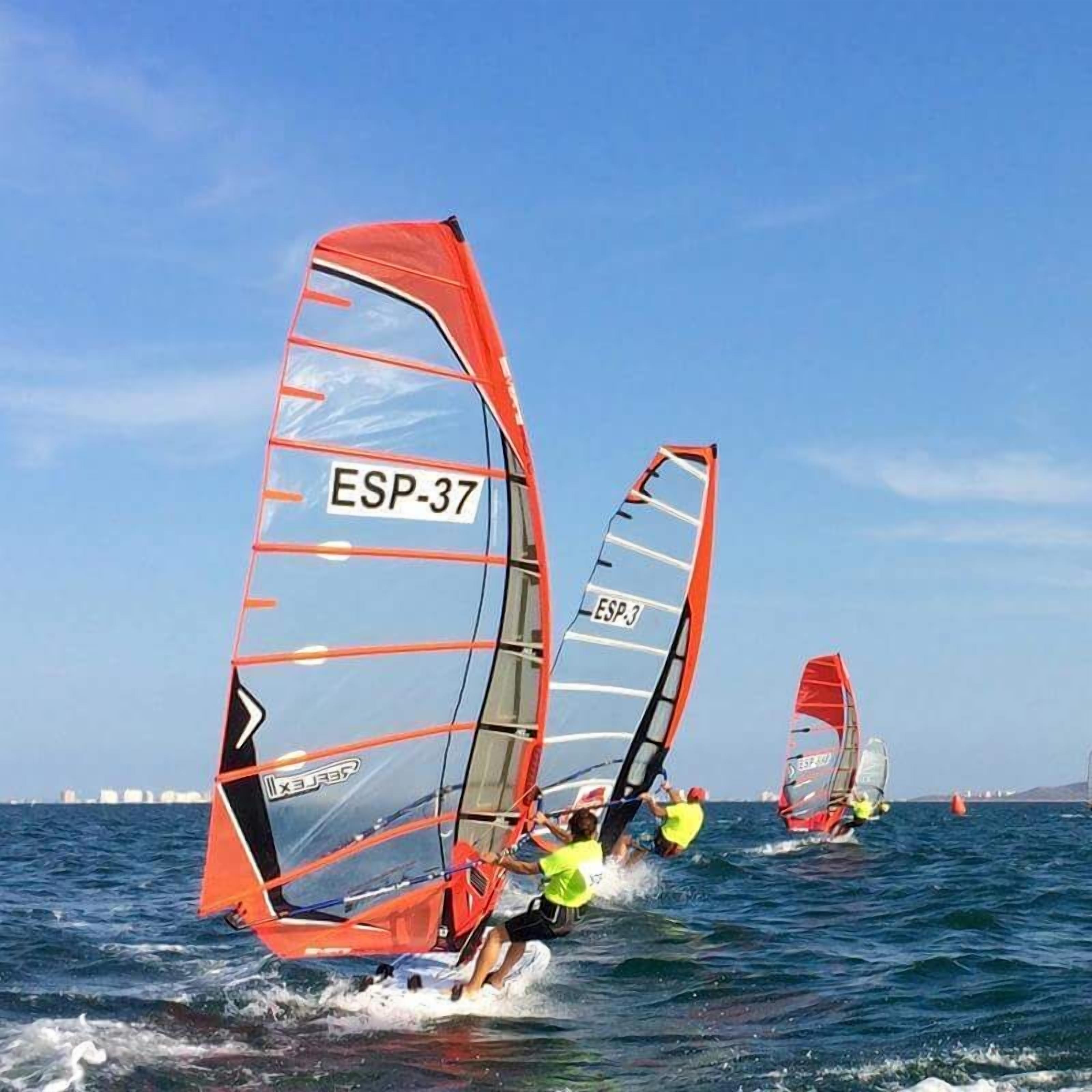 Een groep windsurfers op het water met rode zeilen, waarvan sommige zijn voorzien van nummers zoals ESP-37 en ESP-3.