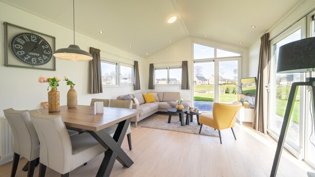 A spacious living room with a dining area, large windows, and a view of the outdoors. - EuroParcs Limburg (Susteren)