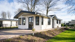 A modern single-story house with a flat roof, large windows, and a small front garden. - EuroParcs Limburg (Susteren)