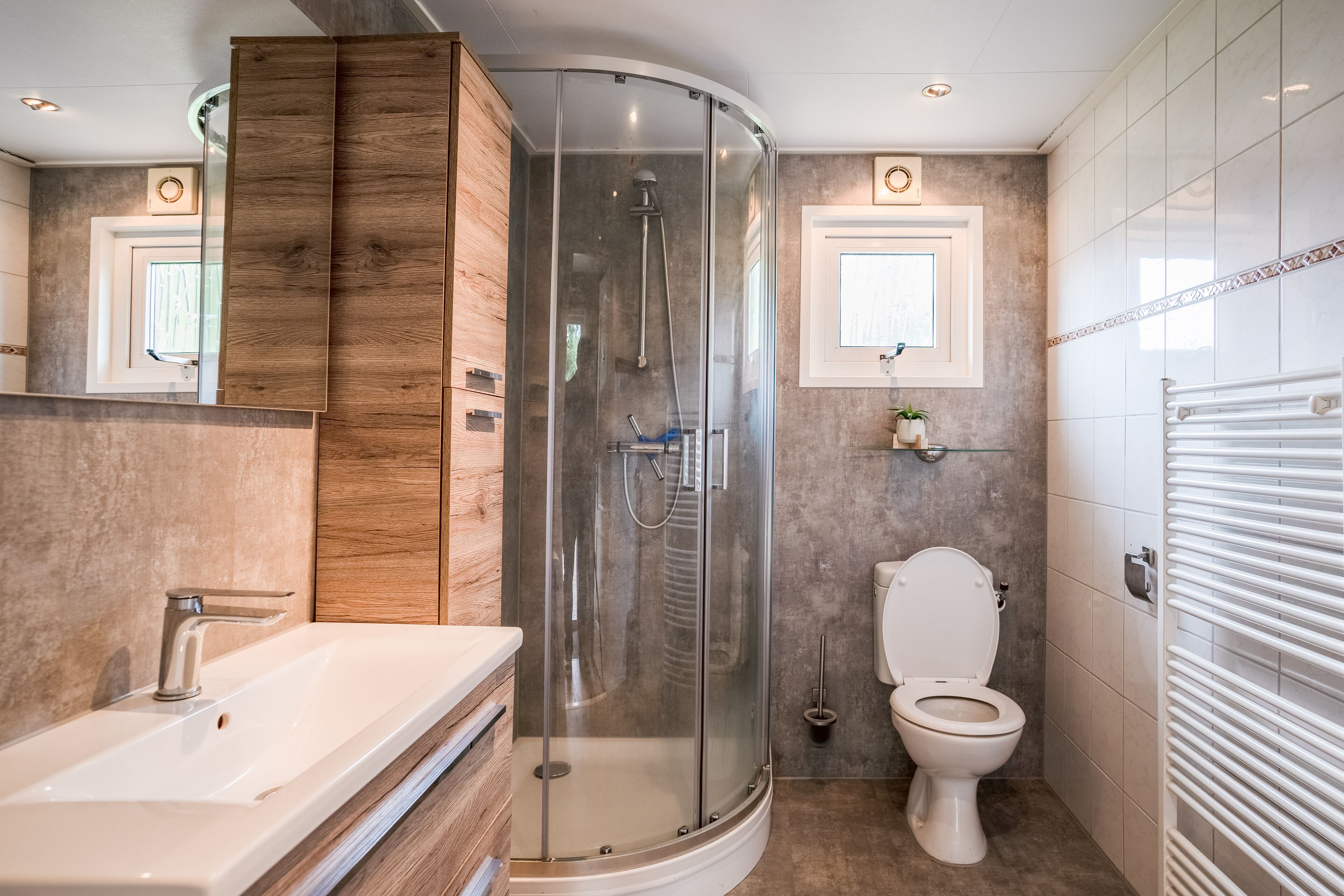 A modern bathroom with a glass-enclosed shower, a white sink, and a toilet.