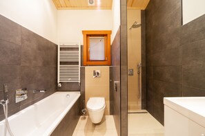 A modern bathroom with a bathtub, toilet, and shower area. - EuroParcs Brunssummerheide (Brunssum)