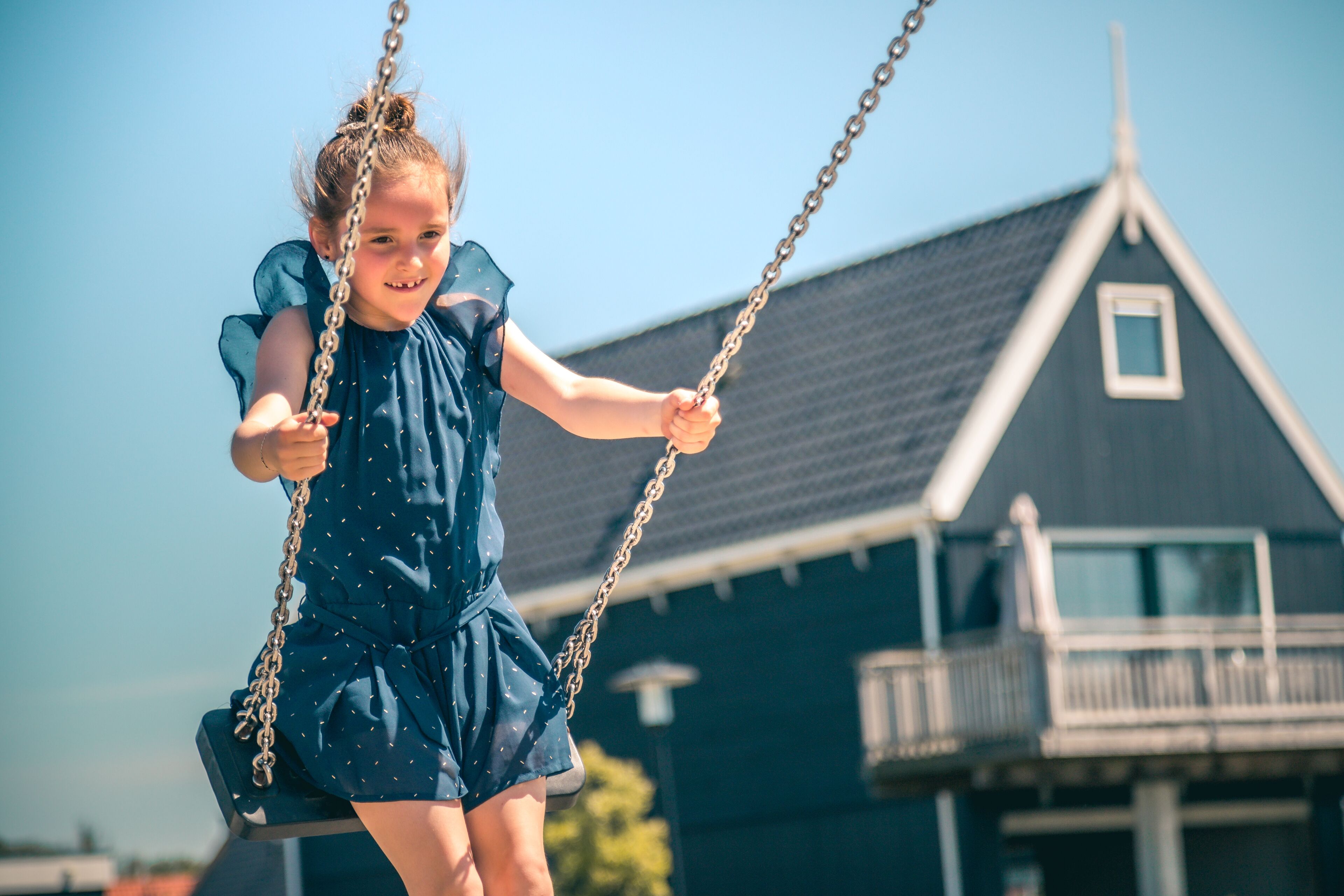 A child on a swing with a house in the background.