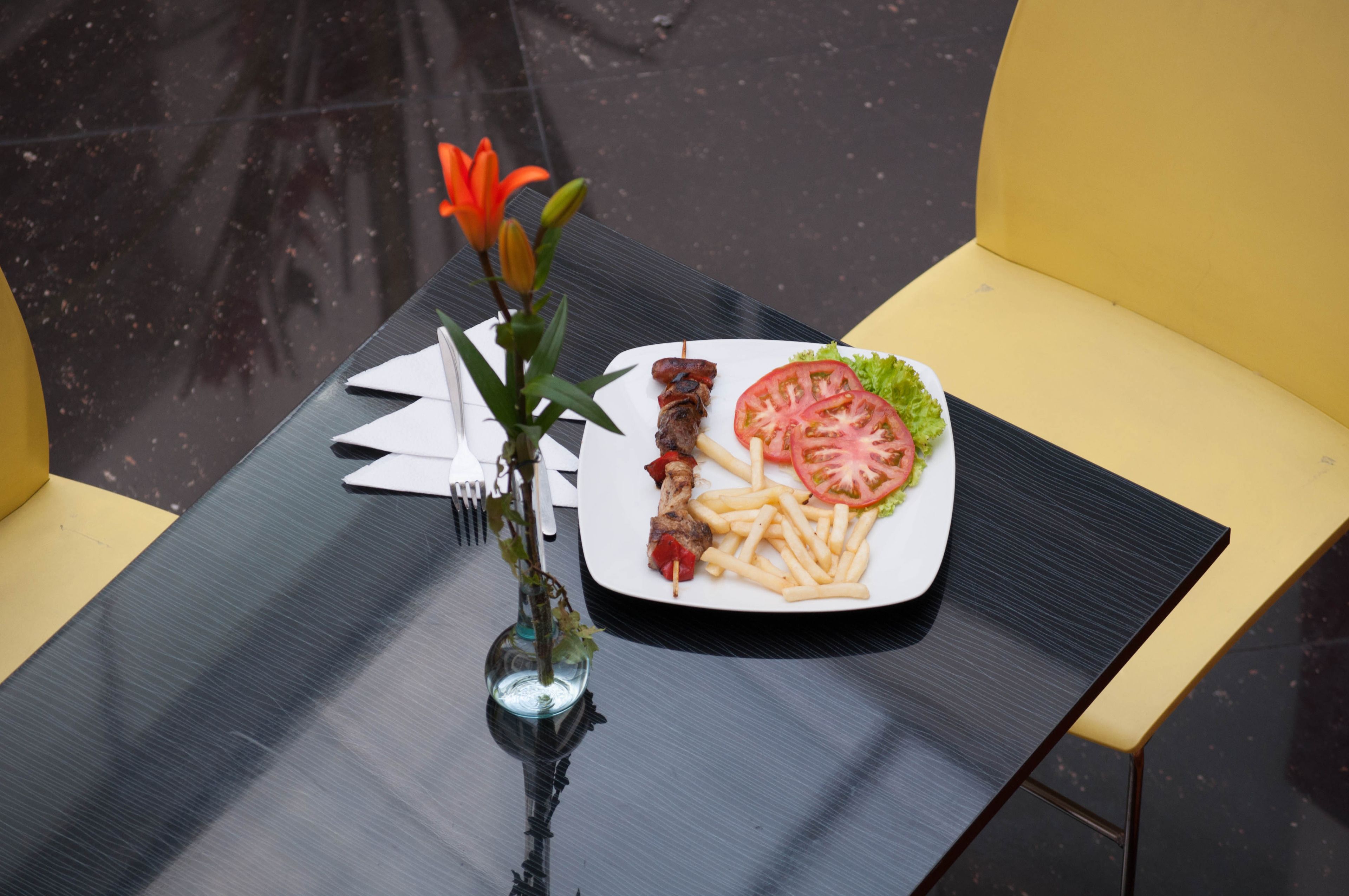 Een eettafel met een bord eten, een vaas met bloemen en een vork en mes.