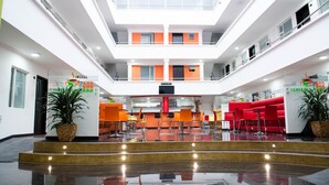 Un atrio de varios niveles con una escalera central, zonas de estar y una cafetería.