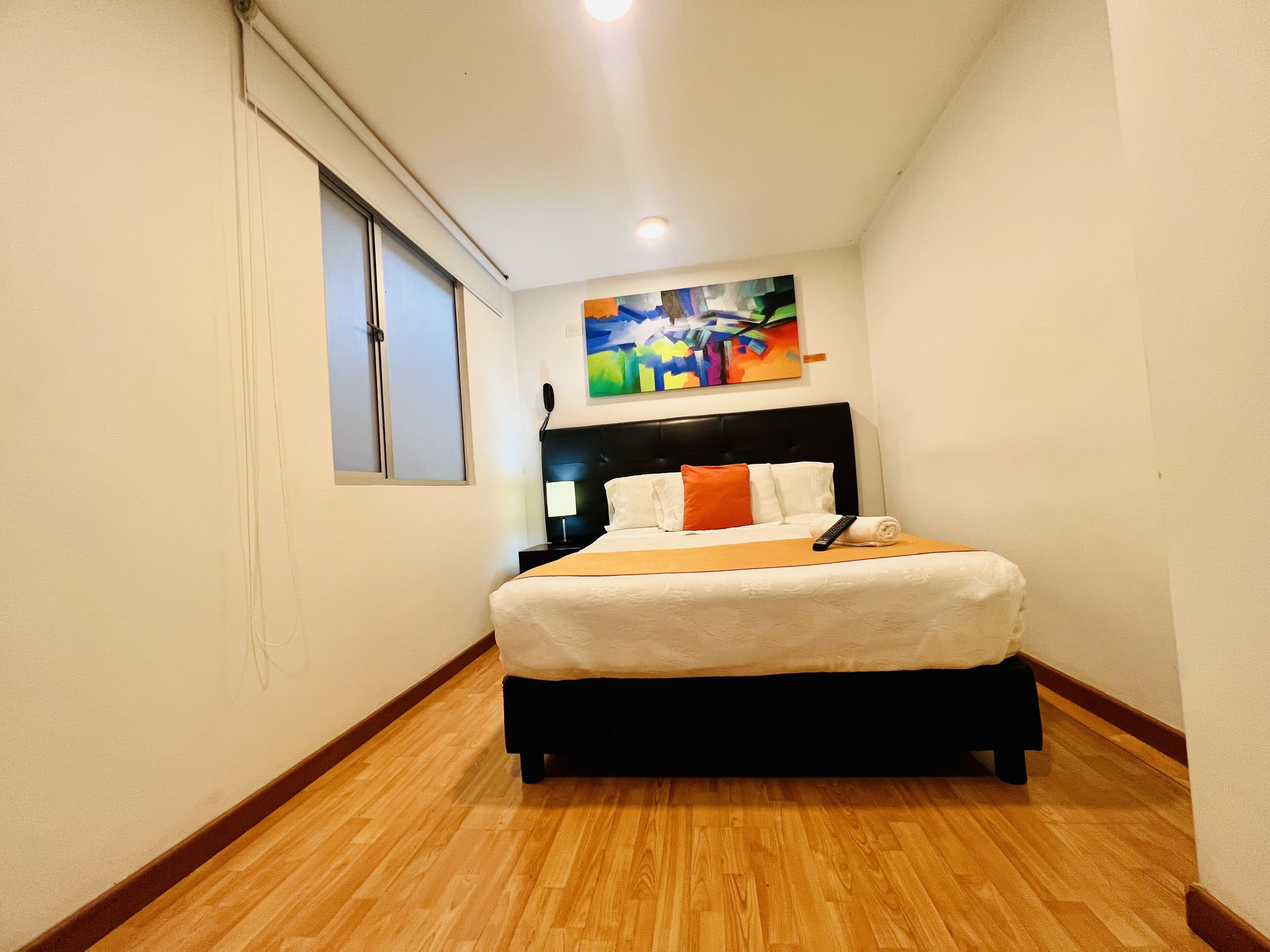 Habitació d'hotel amb un llit, un quadre a la paret i una finestra.