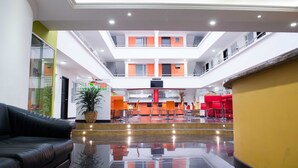 Un hall de hotel con un atrio central, una recepción y zonas de estar.